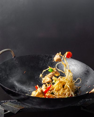 Side view spaghetti in frying pan on black background.